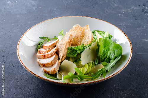 Caesar Salad with grilled chicken on white plate.