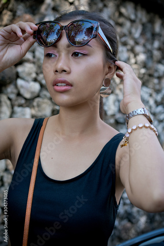 Asian girl; in a black dress on a scooter. Beautiful Balinese women lifestyle portrait