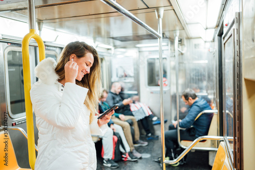 Woman travel in subway with smartphone listening to music