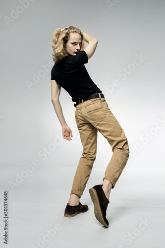 A young handsome guy with long blonde hair, isolated on a light background.