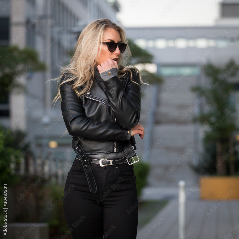 Frau, jung, blond ,schön, modisch, modebewusst und schlank geht im Herbst  mit Lederjacke und engen Jeans und Pumps Hackenschuhe durch die Stadt Stock  Photo | Adobe Stock