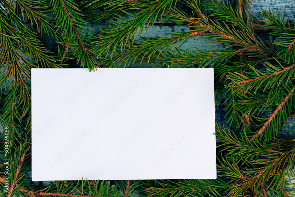 Christmas texture on a blue wooden background surrounded by spruce branches. White form with a place for recording on branches. Christmas texture on a blue wooden background surrounded by spruce branches. White form with a place for recording on branches.