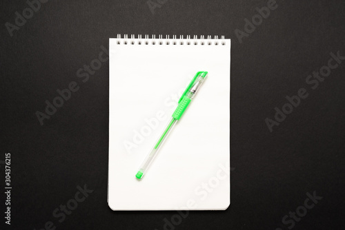 school white notebook with pen on black background
