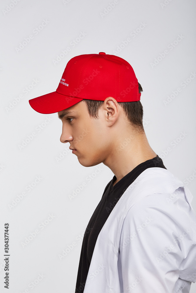 Cropped side photo of a dark-haired man, wearing red baseball cap with lettering Cropped side photo of a dark-haired man, wearing red baseball cap with lettering