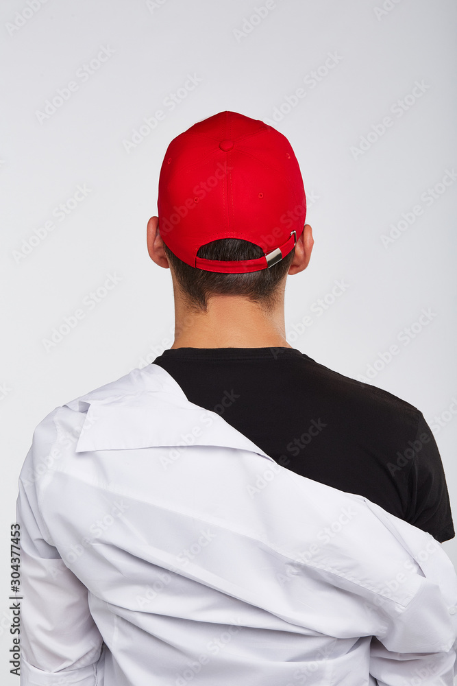 Cropped back view shot of a dark-haired man, wearing red baseball cap,  black t-shirt and white shirt. He is posing on grey background. Stock Photo  | Adobe Stock