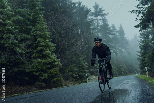 Rennradfahrer im Herbst bei Nebel auf eine Landstraße im Wald