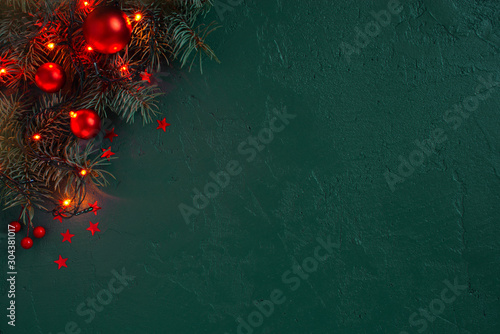 Fir branches and Christmas or New Year red decoration on the textured dark emerald background photo