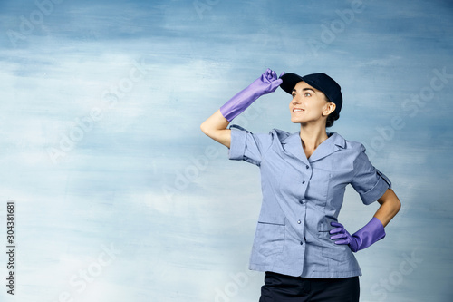 A beautiful young woman in the uniform of a maid and  a baseball cap smiling.  Isolated on a blue background. © Eno1