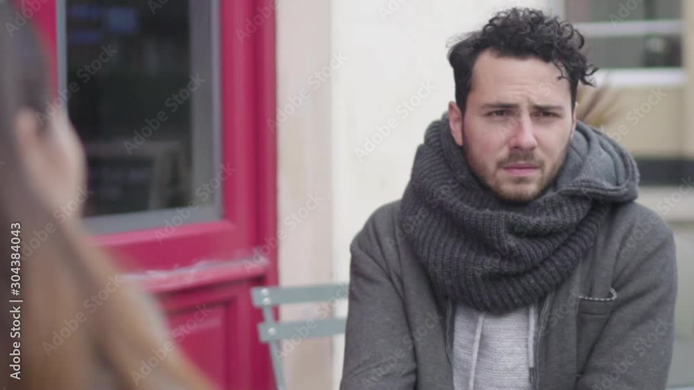 A depressed and unhappy man sitting across to his girlfriend with a sad face while she listens to him A depressed and unhappy man sitting across to his girlfriend with a sad face while she listens to him