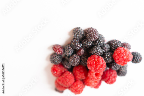 Fragrant sweet red and black raspberries on a white background.