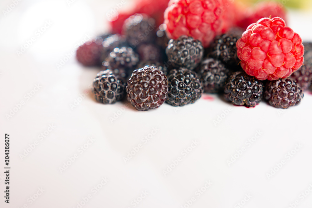 Red and black raspberries closeup on a white background. Red and black raspberries closeup on a white background.