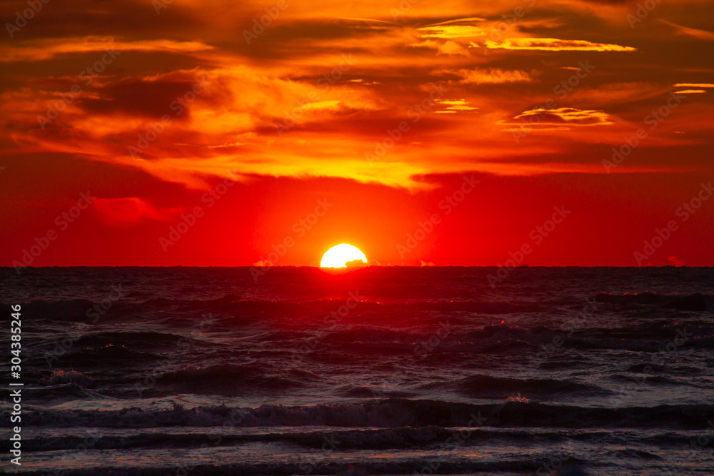 ocean sunrise with dramatic orange and red clouds at Rivazzurra (Rimini/Italy) beach