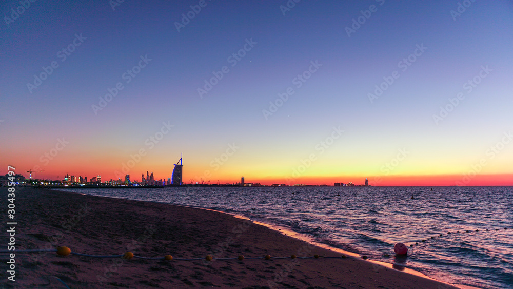 Orange sunset at the beach in Dubai showing skyline