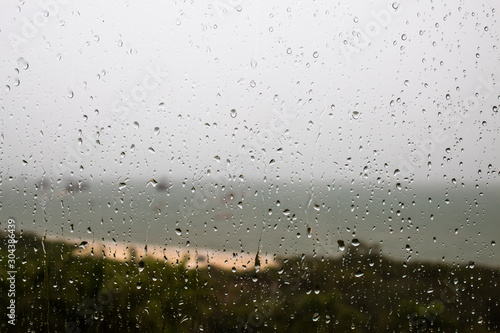 Gotas de chuva na janela ao fundo silhueta da Praia de Cachoeira do Bom Jesus, Florianópolis - Santa Catarina, Brasil