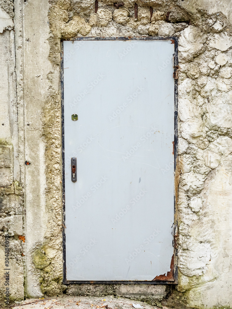 Iron gray door without a handle in a concrete wall