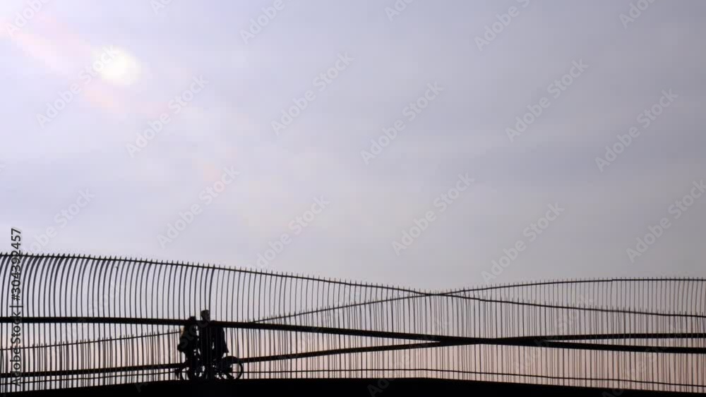 Silhouette of riding bicycle woman and couple walking over the bridge. Silhouette of riding bicycle woman and couple walking over the bridge.