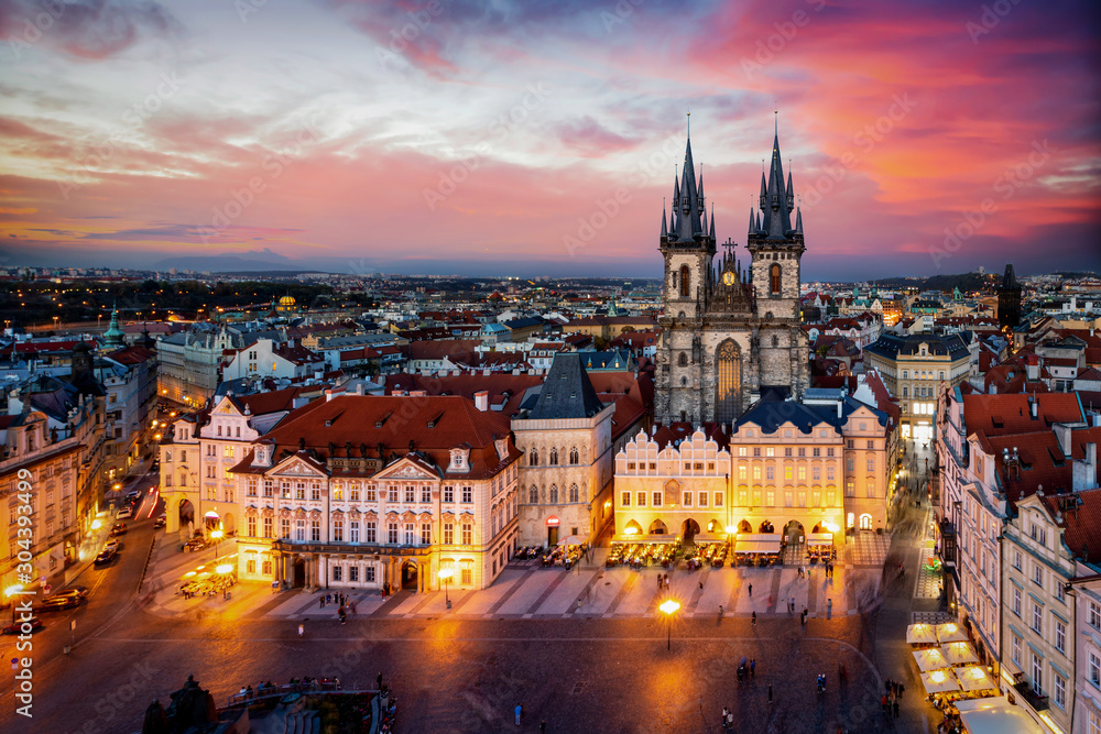 Prag am Abend: Blick auf die Marienkirche am alten Platz der Altstadt mit Lichtern und rotem Himmel, Tschechiche Republik - obrazy, fototapety, plakaty 