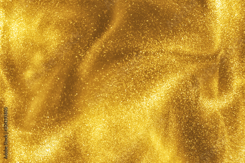 Abstract elegant, detailed gold glitter particles flow with shallow depth of field underwater. Holiday magic shimmering luxury background. Festive sparkles and lights. de-focused. photo