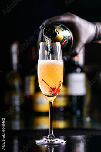Obraz na plátně bartender pours bellini champagne cocktail into a glass with cherry