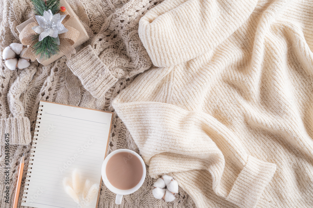 Autumn or winter composition. Gift box Coffee cup, notebook, anise stars, beige sweater on cream color knitted blanket background. Flat lay top view copy space. Autumn or winter composition. Gift box Coffee cup, notebook, anise stars, beige sweater on cream color knitted blanket background. Flat lay top view copy space.