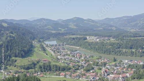 Aerial vertical tilt up drone shot over town of Dravograd in lush green valley below photo