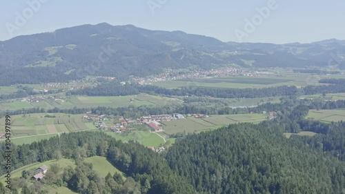 Aerial pan drone shot over town of Dravograd in lush green valley below photo