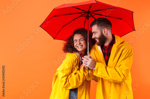Loving couple posing in yellow raincoats isolated