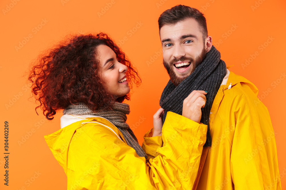 Loving couple posing in yellow raincoats isolated