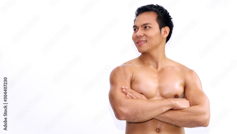 Handsome young man smile cross his arm while standing isolated on white background. Bodybuilder guy have biceps looking at something while arms cross with copy space. Good healthy concept
