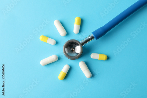 Flat lay with pills and stethoscope on blue background, top view and space for text