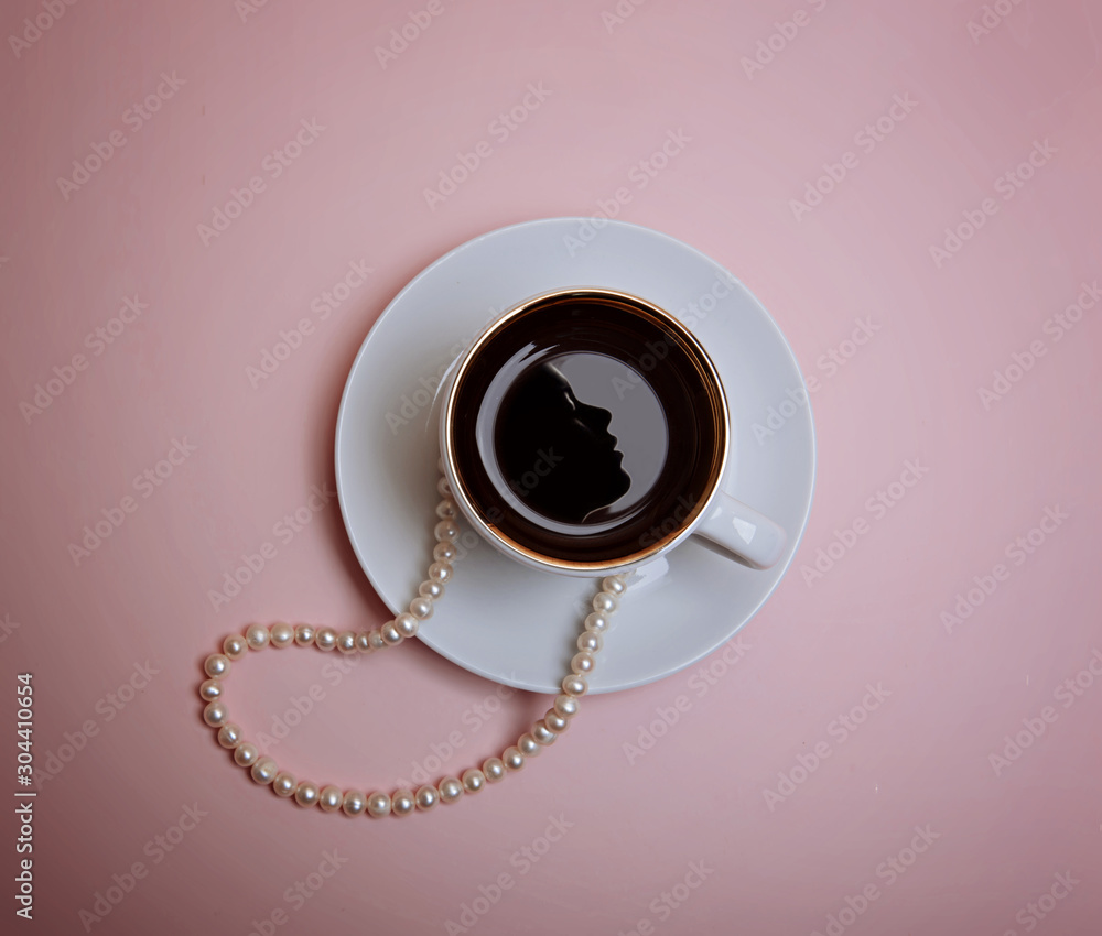 A cup of espresso with reflection of a female face silhouette, pearl beads and a few beads are on a pink background. Flatlay A cup of espresso with reflection of a female face silhouette, pearl beads and a few beads are on a pink background. Flatlay