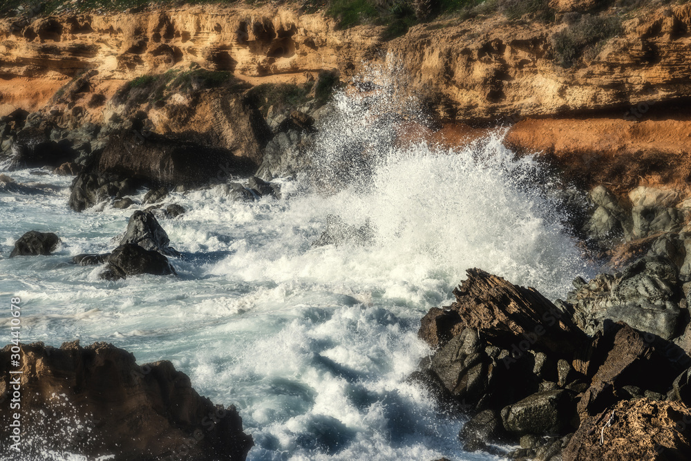 Wave crashing against Alghero rocky shore