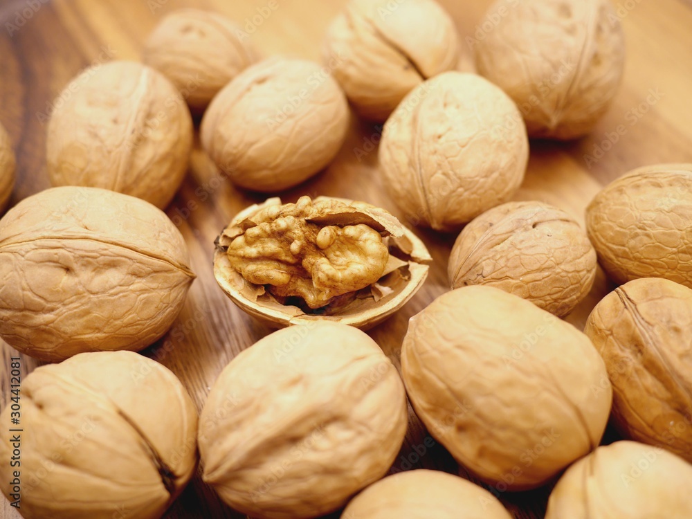Photo of several walnuts in shell and one open walnut between them. Photo of several walnuts in shell and one open walnut between them.