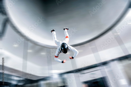 Skydive. Indoor skydiving in wind tunnel. Men fly in black helmet and white suit. 