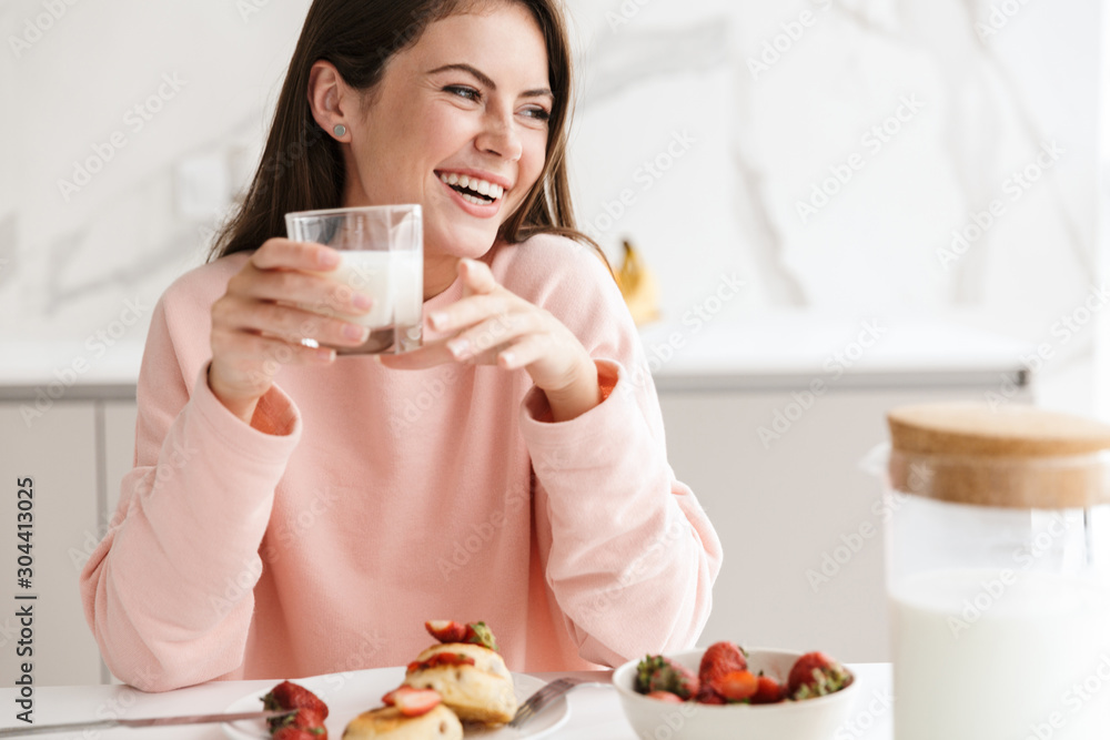 Beautiful smiling young girl having tasty healthy breakfast