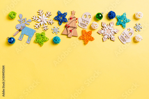 Top view of yellow background with New Year toys and decorations. Christmas time concept with copy space