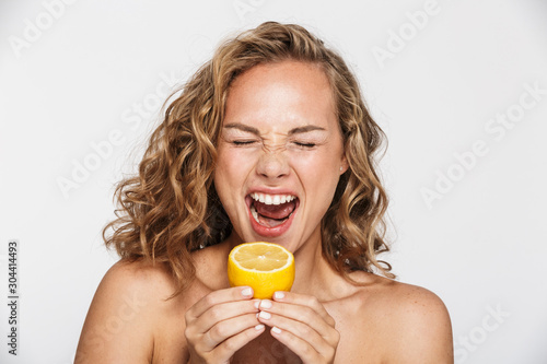 Image of displeased half-naked woman grimacing and eating lemon