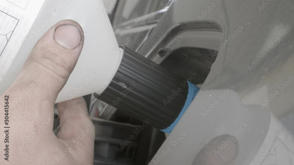 Person's hand with greasy fingers pouring an additive into the tank of a car. Person's hand with greasy fingers pouring an additive into the tank of a car.