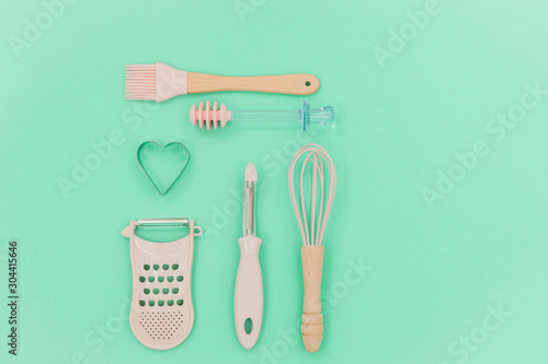 Flatlay  pink kitchen utensils on neo mint background. Greater, whisk and iron cooking form. Top horizontal view copyspace love cookong concept photo