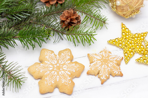 Christmas gingerbread snowflakes lie on a white wooden background. Christmas decorations and natural spruce on the background.