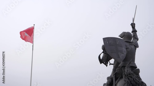 Looking up at the Vytis coat of arms on a flag next to the Freedom Warrior statue in Kaunas castle, Lithuania photo