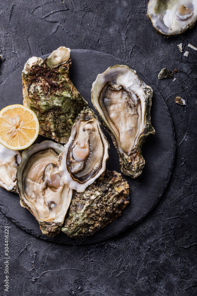 Fresh open Oysters. Healthy sea food. Dinner in restaurant. Gourmet food. Dark background. Top view Fresh open Oysters. Healthy sea food. Dinner in restaurant. Gourmet food. Dark background. Top view