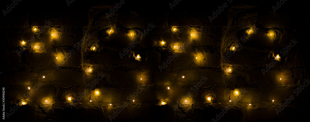 Garland lights on the dark brick wall. Date 2020 New Year Garland lights on the dark brick wall. Date 2020 New Year