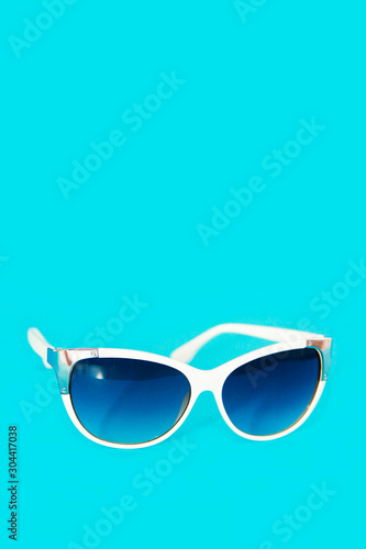 sunglasses in a white plastic frame and blue glasses lenses on a blue background © Mari