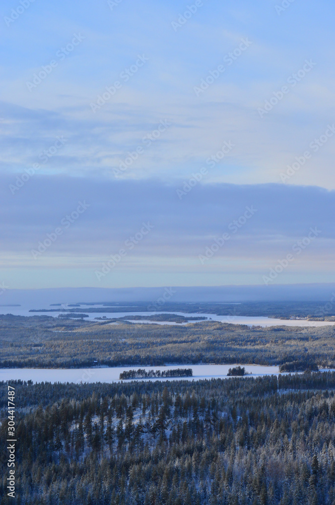 Finnisht winter, Kuusamo. Landscape from Konttainen. Fading daylight, colorful horizon and frozen lakes. Mist descends over the forested hills.
