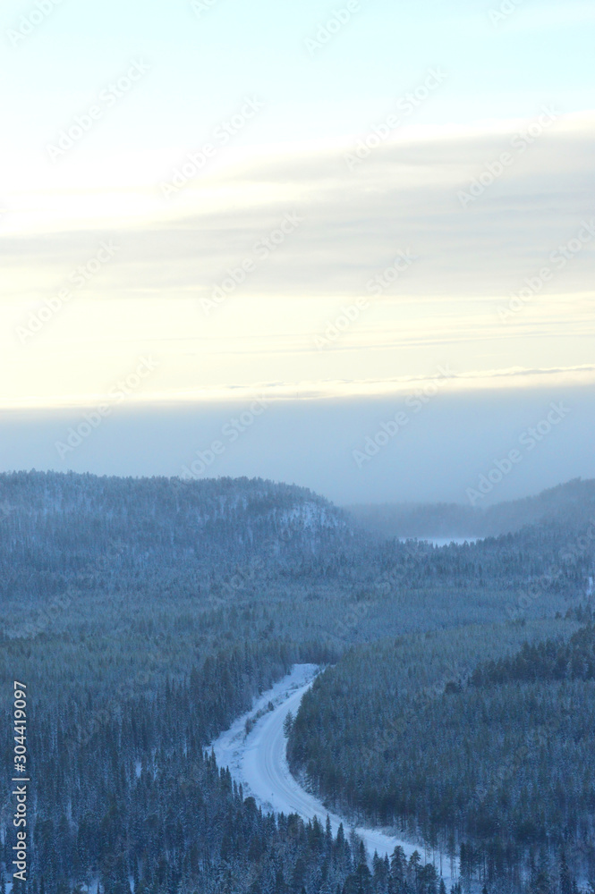 Finnisht winter, Kuusamo. Landscape from Konttainen. Fading daylight and road through the forest. Finnisht winter, Kuusamo. Landscape from Konttainen. Fading daylight and road through the forest.