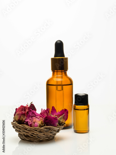 rose essential oil with dried rose on white background