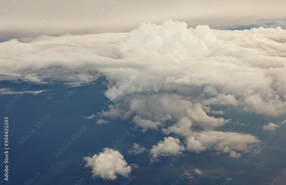 Aerial view from the plane of white soft fluffy clouds over the green landscape in sky in sunny day, toned Aerial view from the plane of white soft fluffy clouds over the green landscape in sky in sunny day, toned