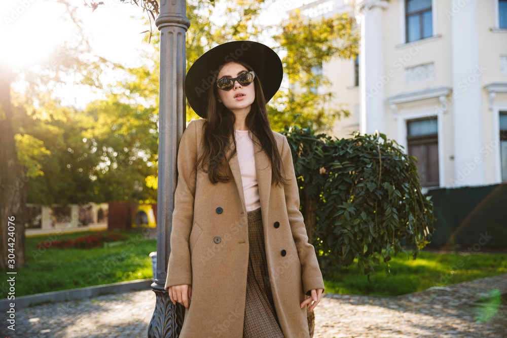 Fototapeta premium Portrait of adorable woman in sunglasses walking in green garden outdoors