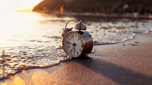 Vintage clock on the beach of Poetto, Cagliari, sunrise, soft waves and sunlight